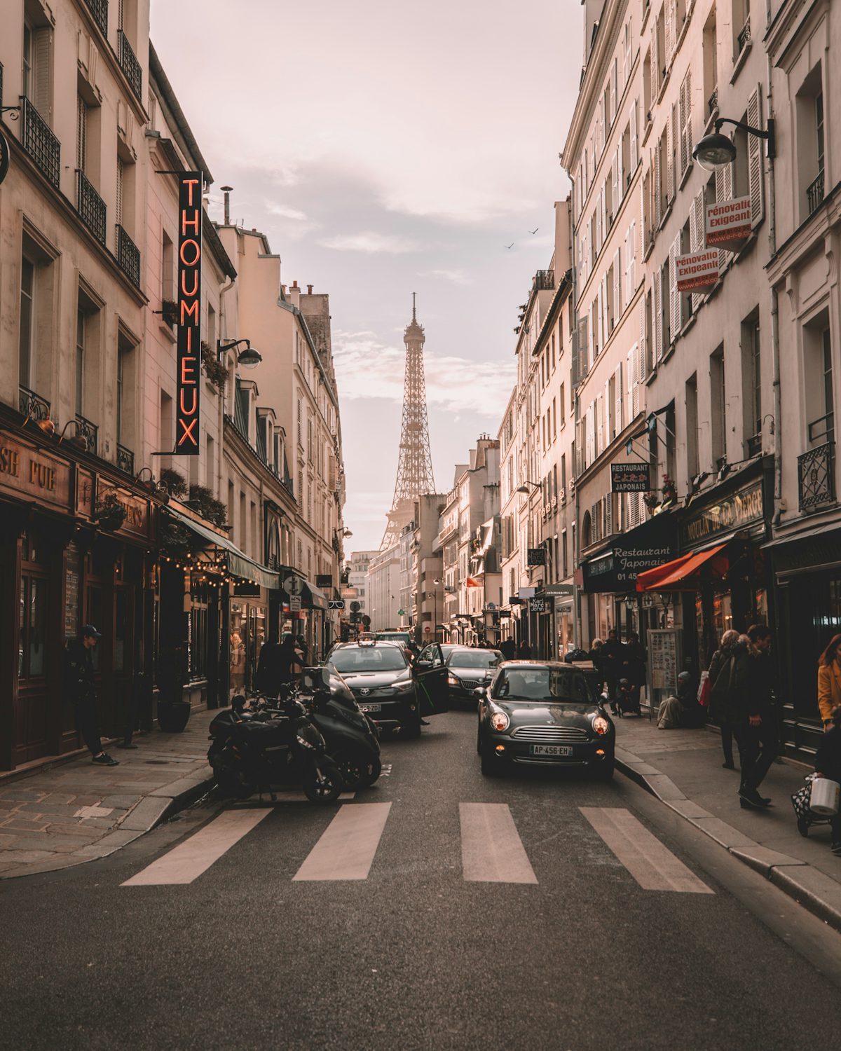 A Paris street at dusk with the Eiffel Tower in the distance