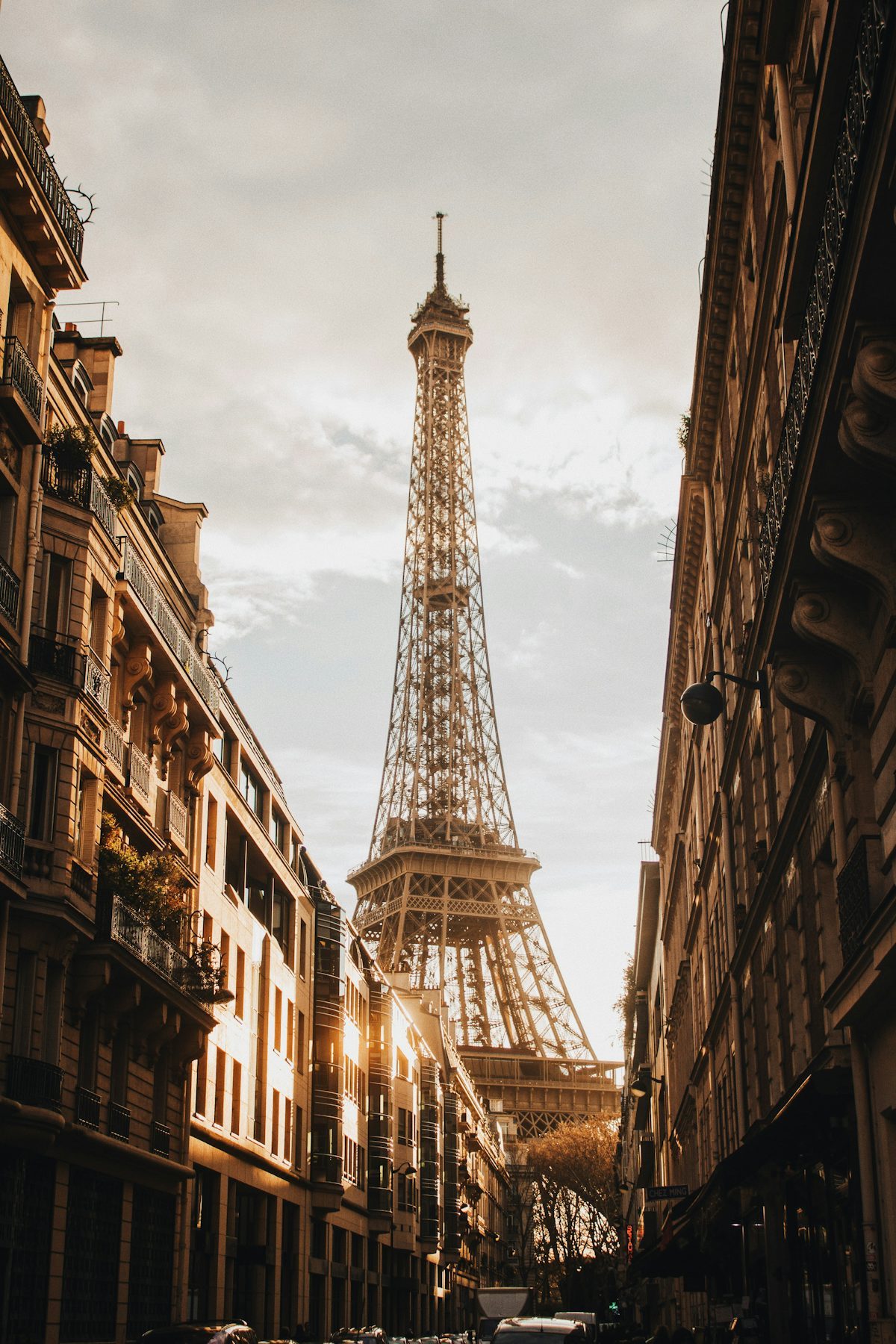 The Eiffel Tower glowing at golden hour, framed by a Parisian street