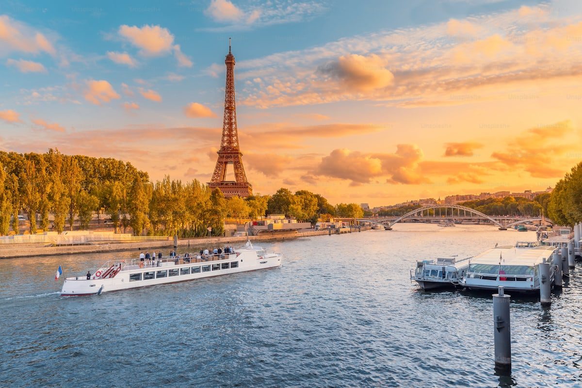 Boats on the Seine with the Eiffel Tower glowing at sunset