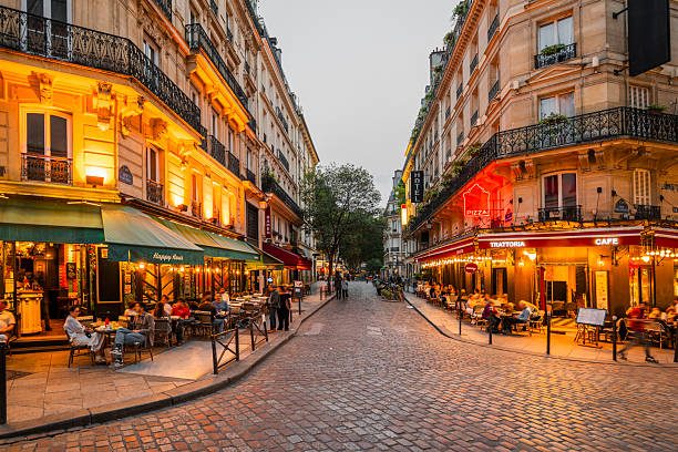 A Parisian café-lined corner glowing in the evening, golden light spilling onto cobblestones
