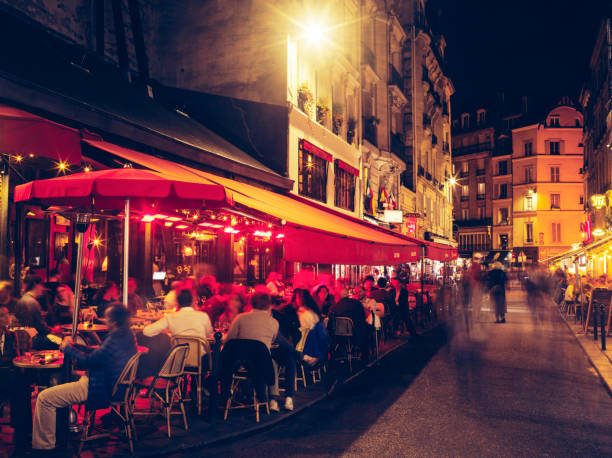 A Parisian café terrace at dusk, glowing red awnings and golden lamplight